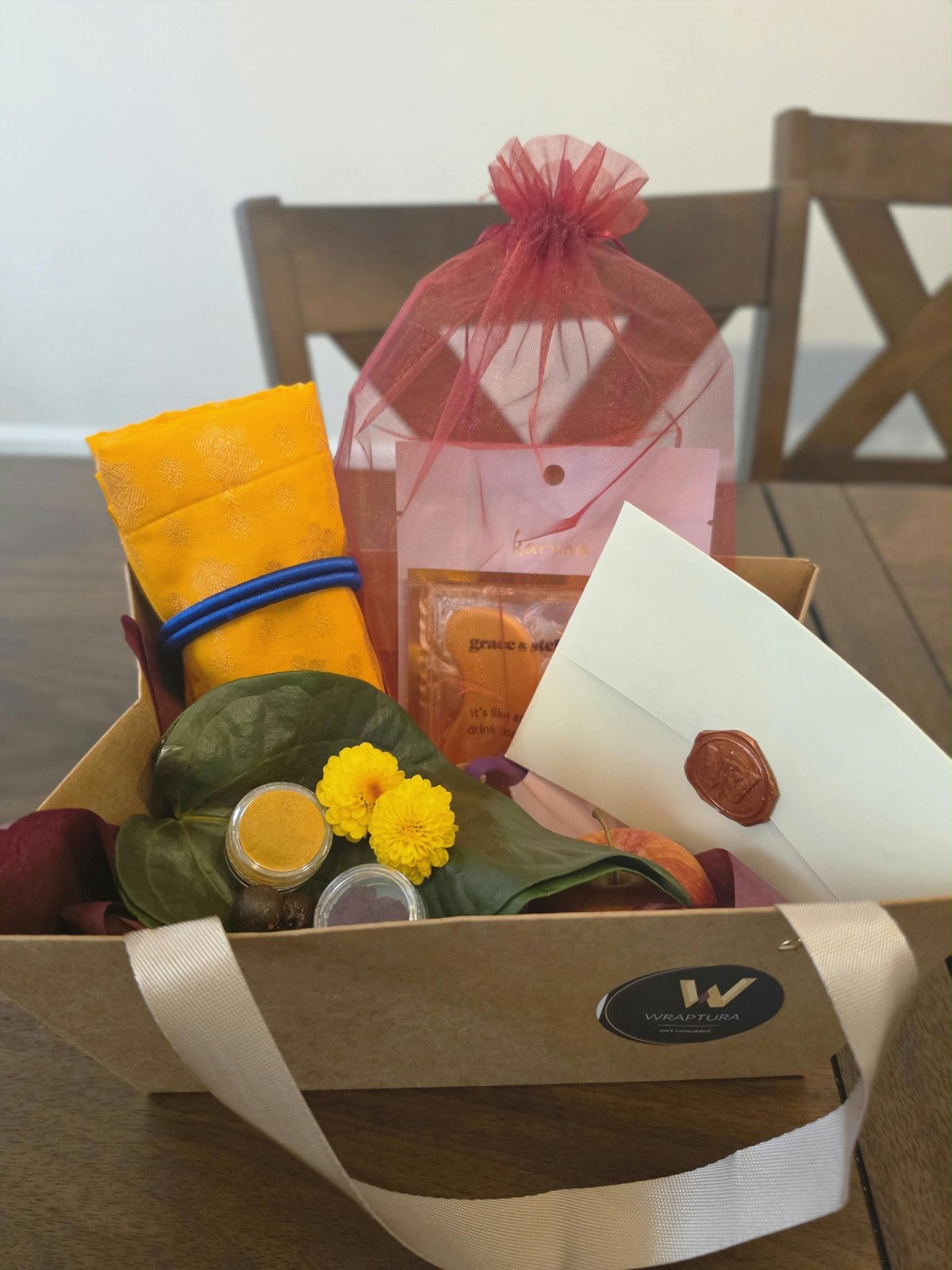 Close view of the same Wraptura tray showing the oxblood wax seal on a cream envelope and the Wraptura seal on the kraft carrier